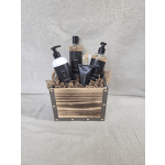Wooden crate filled with black-labeled bath products and a small brush on shredded paper filler