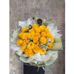 Bouquet of yellow roses with white filler flowers wrapped in pale paper
