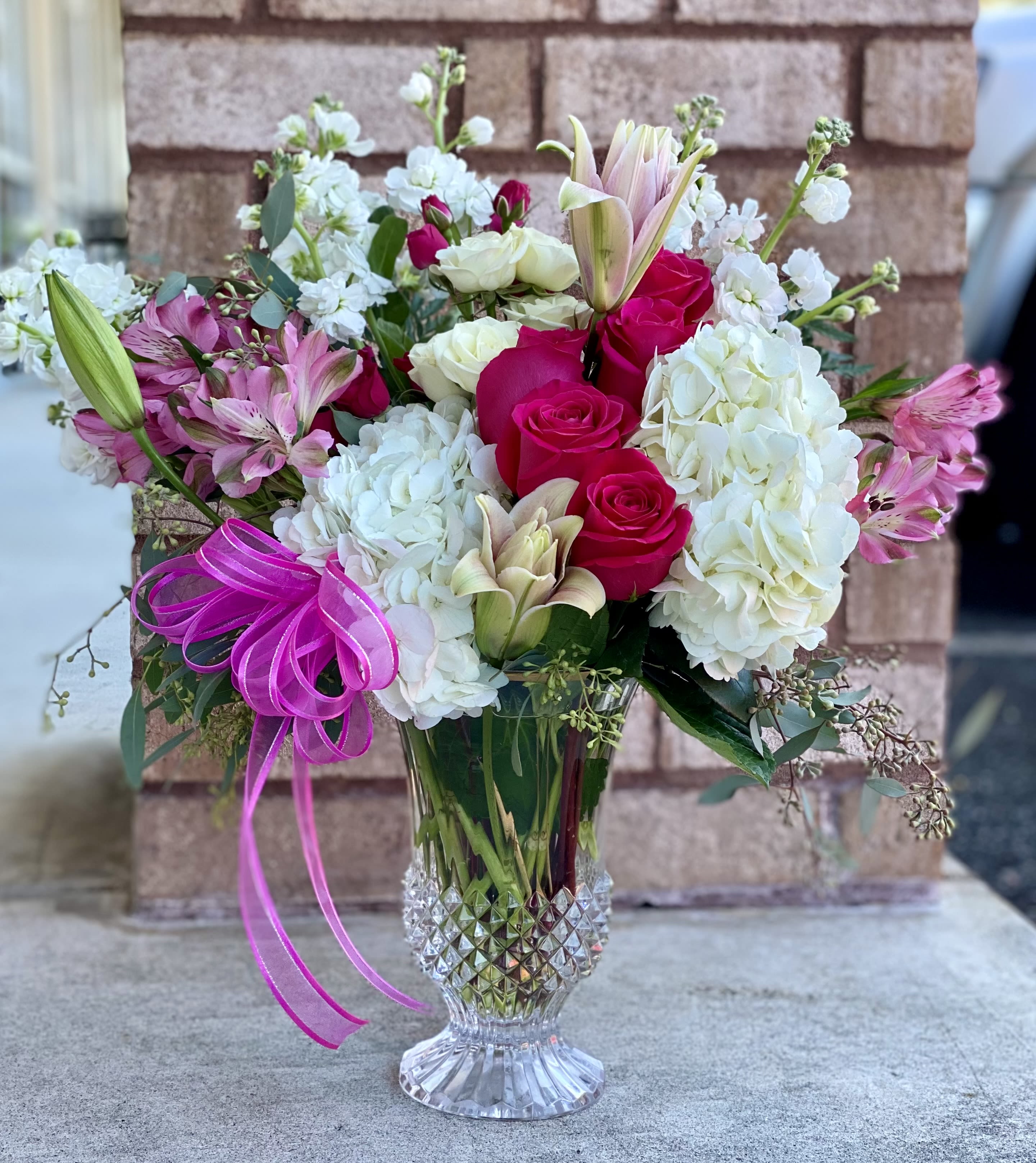 Bouquet of pink roses, white hydrangeas, and lilies in a clear glass vase