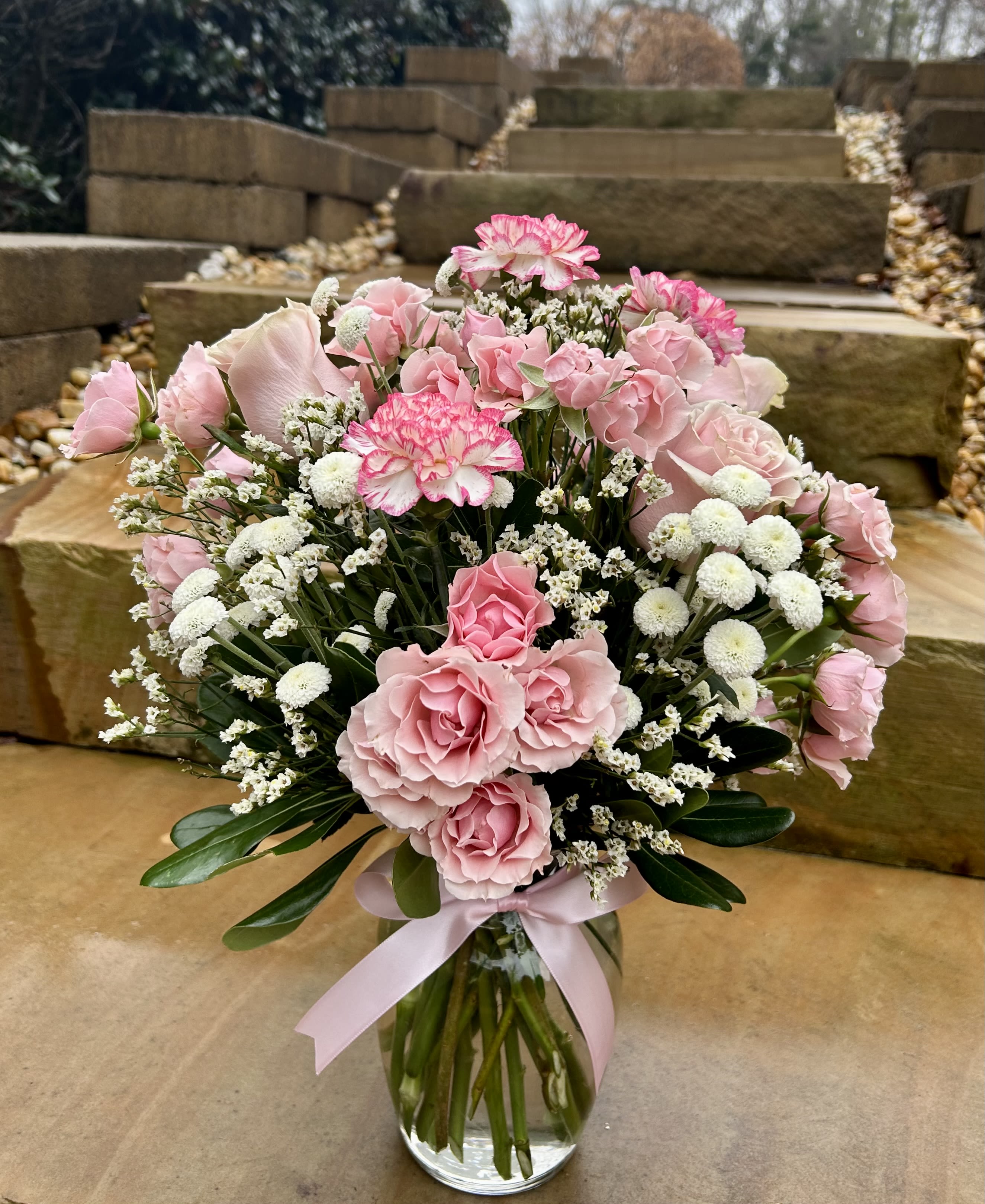 Pink roses and carnations in a glass vase with a pink ribbon