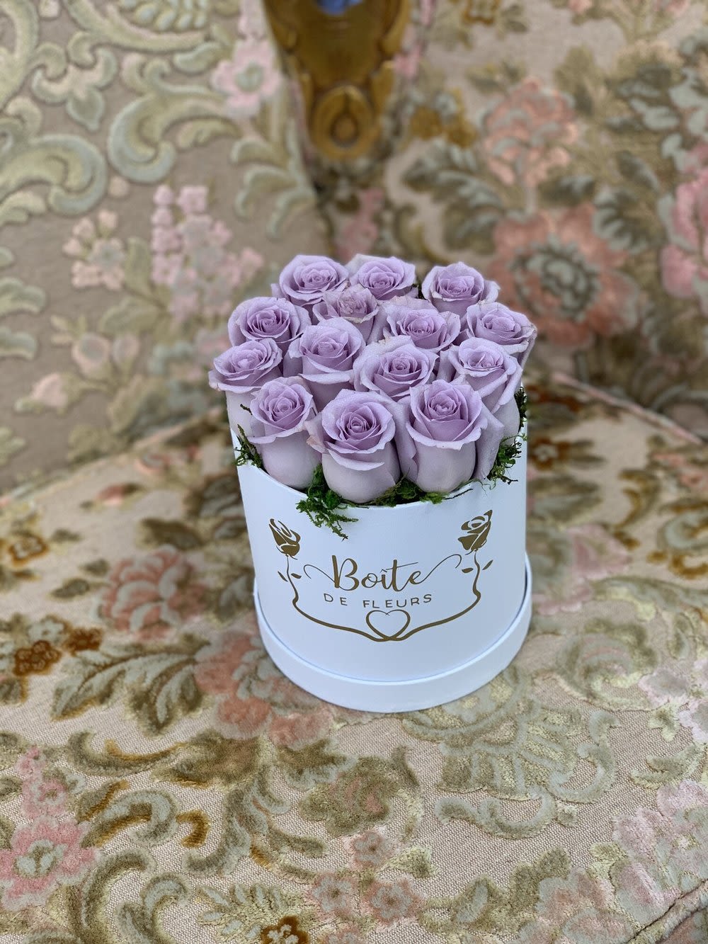 Lavender roses arranged in a white round box