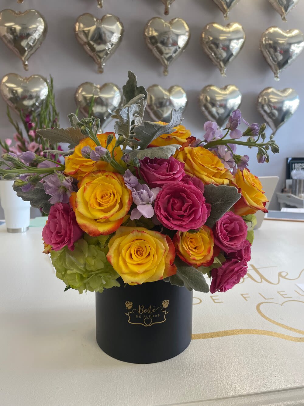Yellow and pink roses arranged in a black hat box