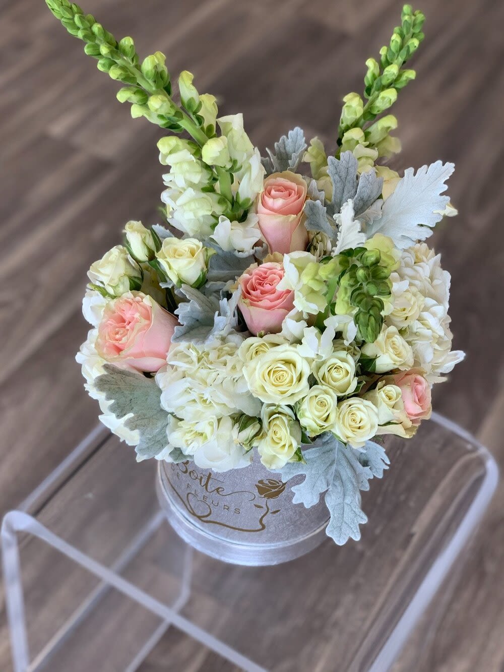Pink and white roses in a round box with silver foliage