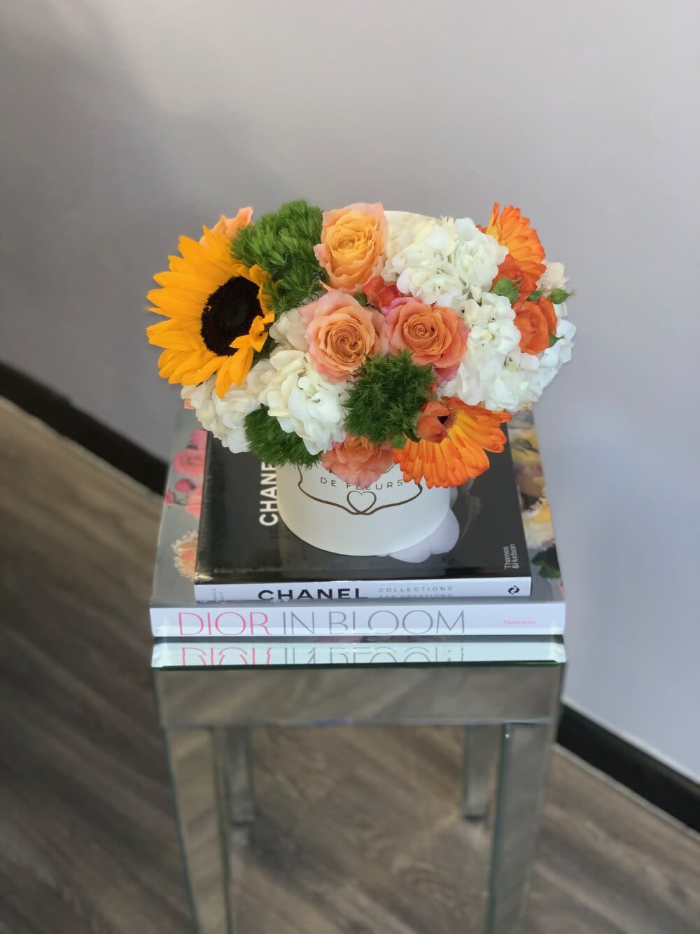 Bouquet of sunflowers, roses, and white hydrangeas in a white hat box