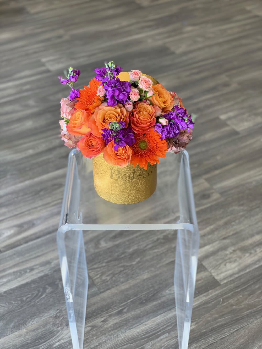 Bouquet of orange and purple flowers in a gold box