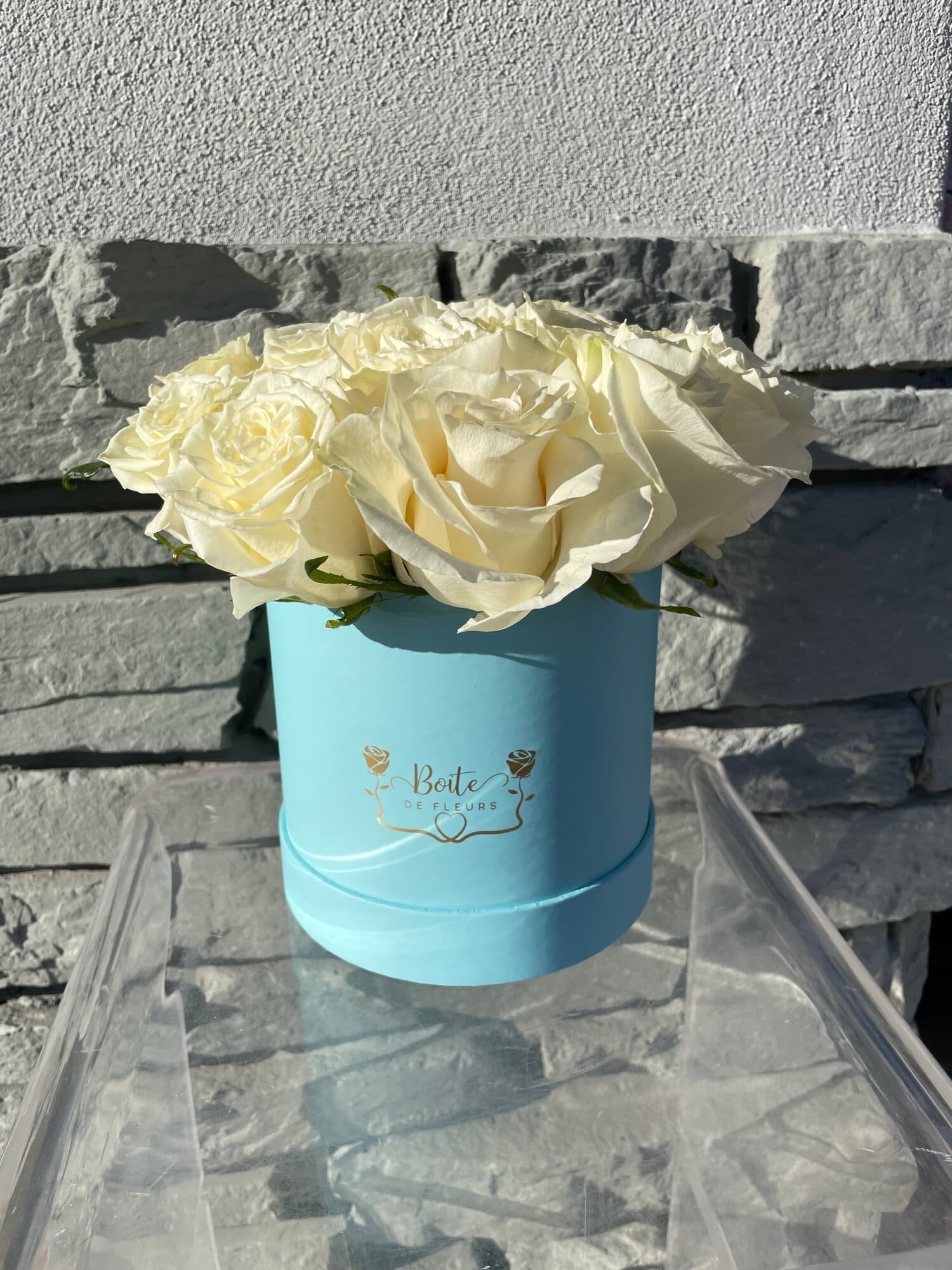 White roses arranged in a light blue round box