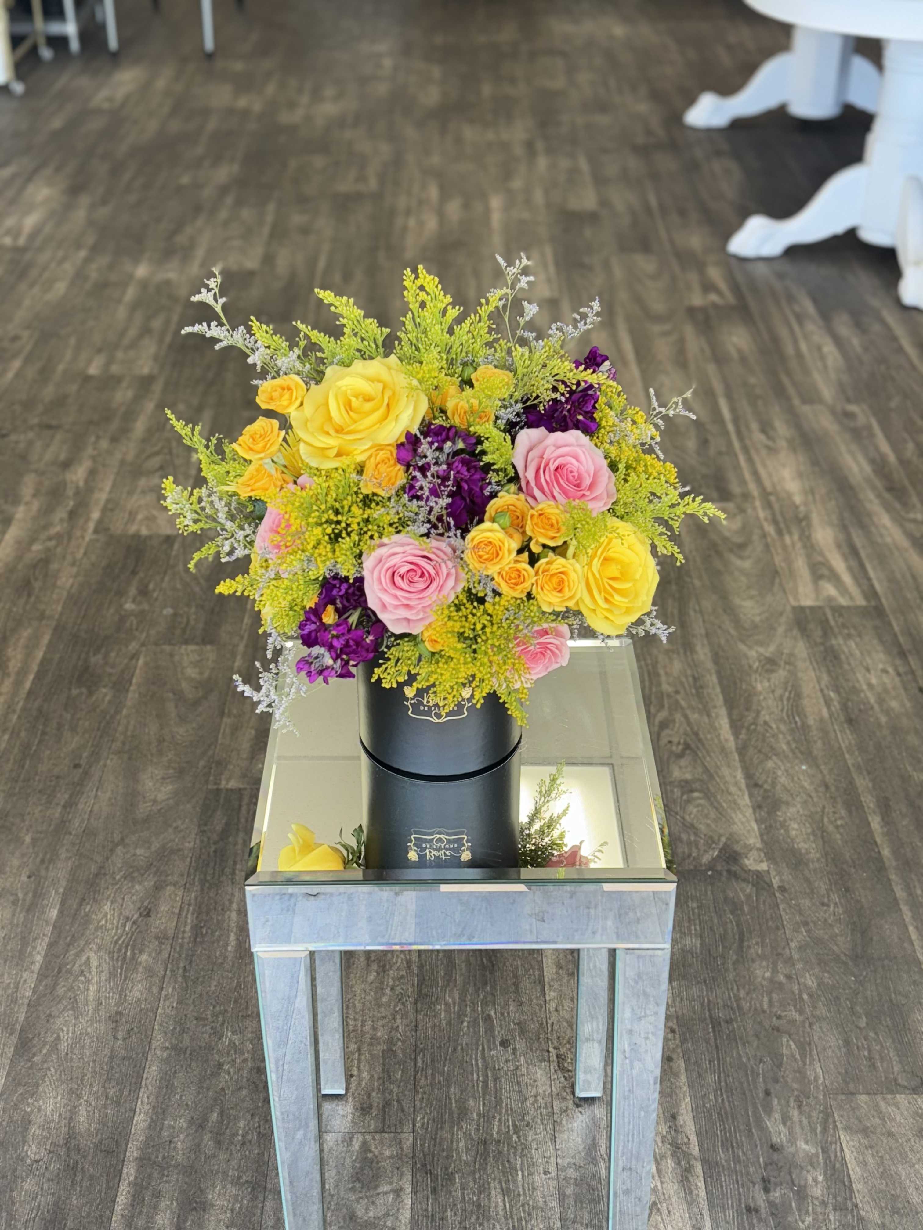 Bright bouquet of yellow, pink, and purple roses in a black box