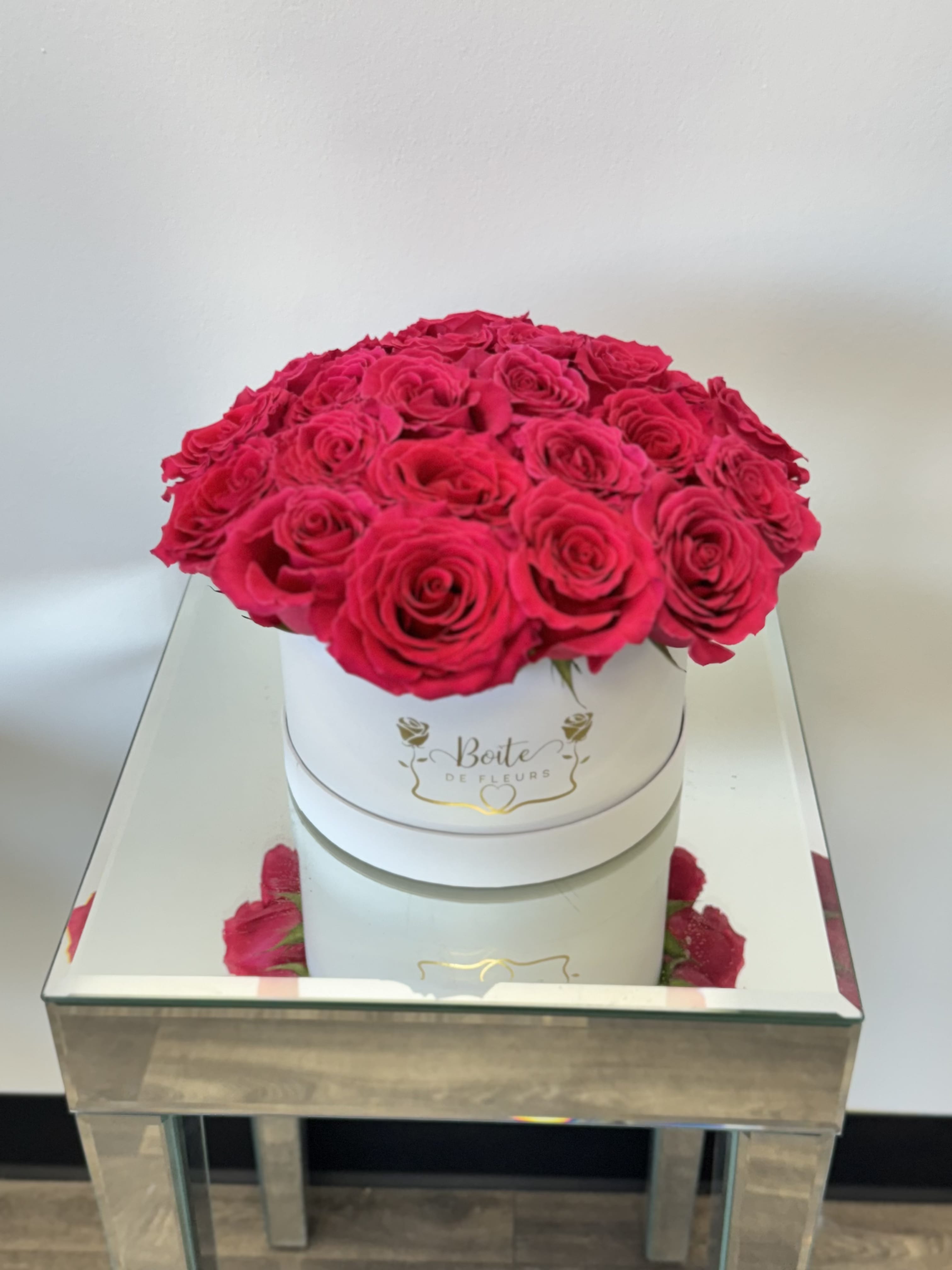 Round box of hot pink roses on a mirrored table