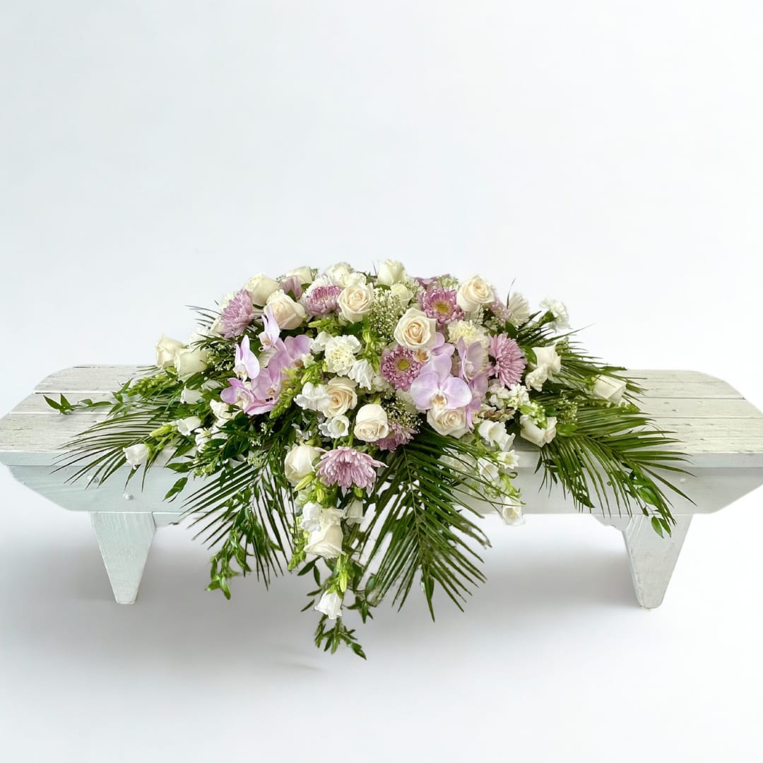 White and blush floral arrangement on a low white bench