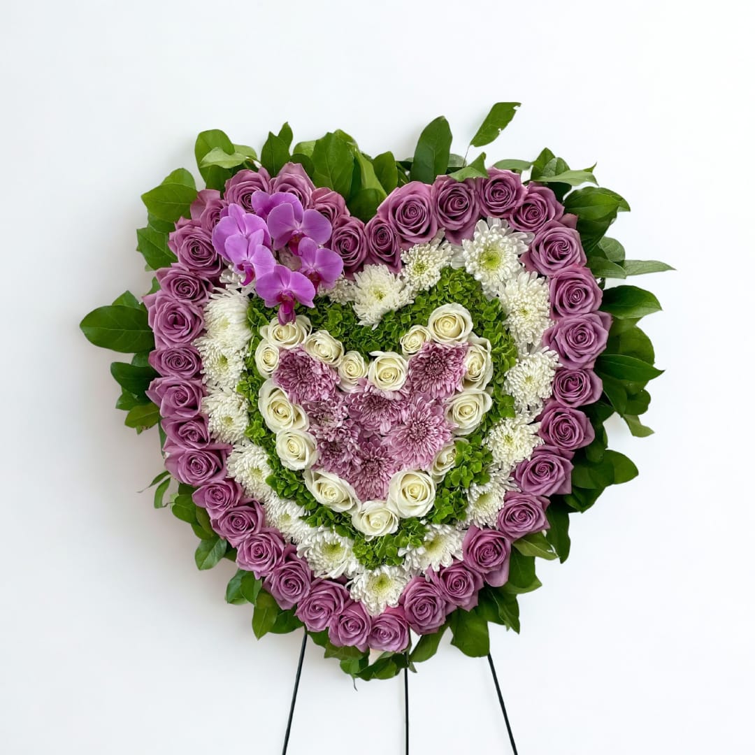 Heart-shaped floral arrangement with purple, white, and pink flowers