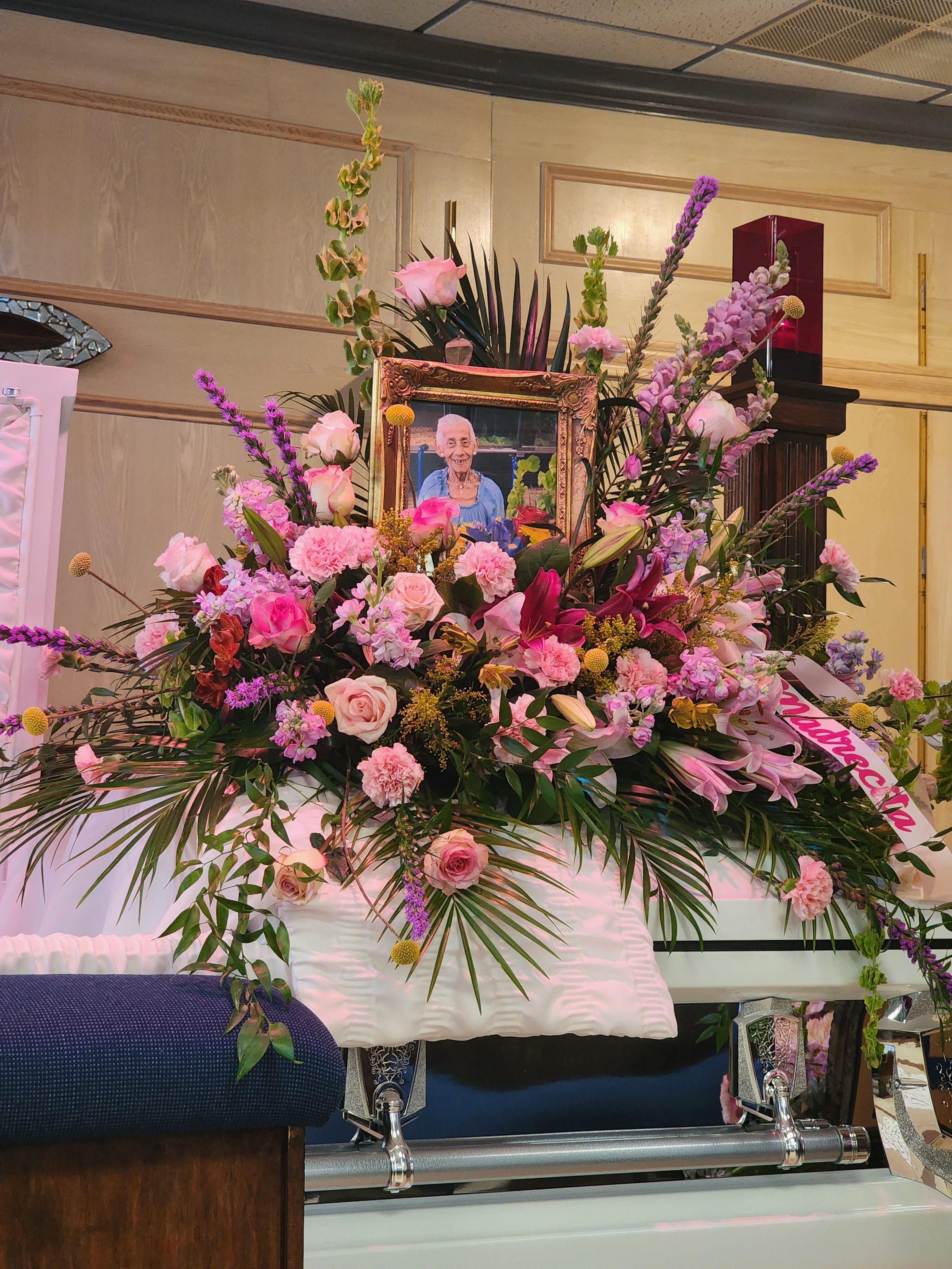 Abuelita’s Heavenly Garden - Casket piece with pink roses, pink carnations, and purple stock.