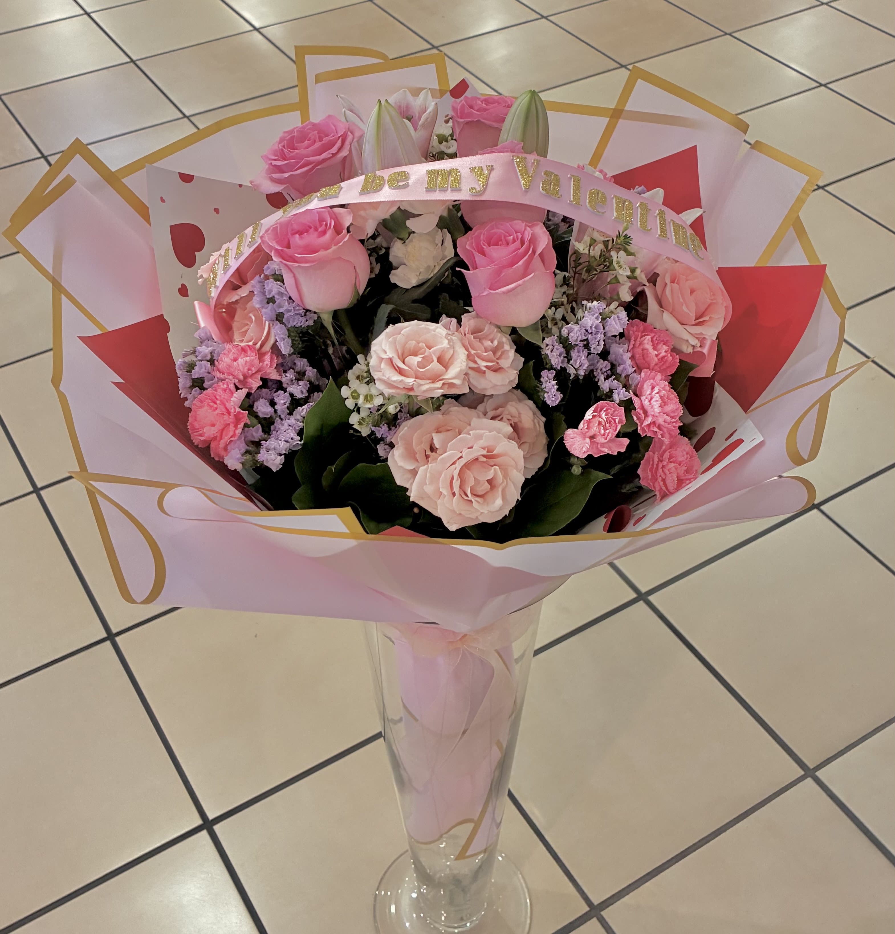 Pink rose bouquet in a clear vase with a Valentine ribbon