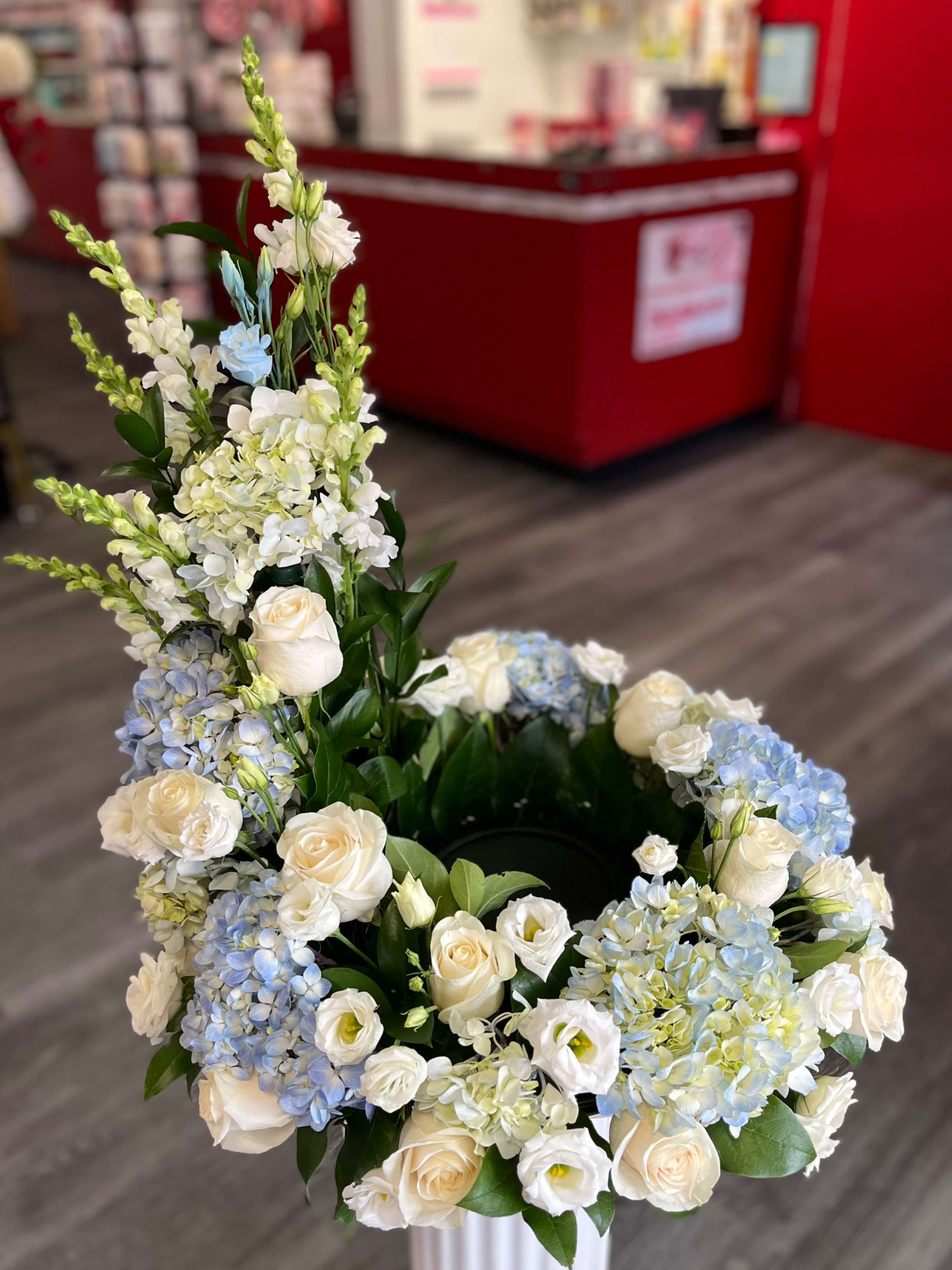 White and blue floral arrangement with roses and hydrangeas in a vase