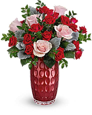 Arrangement of red and pale pink roses in a tall textured red vase