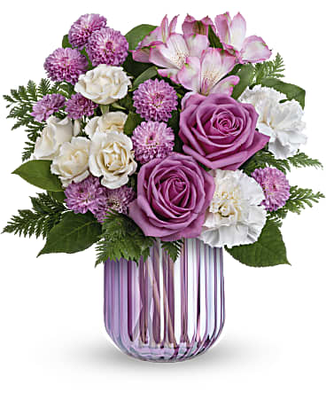 Lavender and white mixed flower arrangement in a ribbed purple glass vase