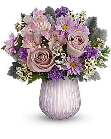 Pastel bouquet of pink roses, lavender daisies, and alstroemeria in a ribbed lavender glass vase