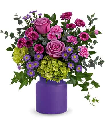 Lavender roses, pink carnations, asters and green hydrangea in a matte purple vase