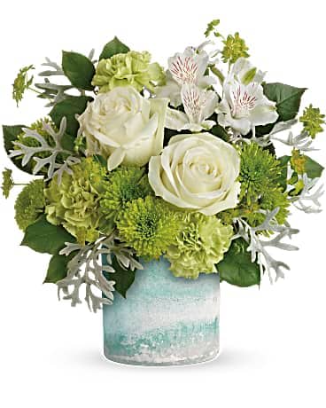 Teleflora's Seaside Roses Bouquet - Like an invigorating ocean breeze, this fresh bouquet of white roses and glorious green blooms is a beautiful pick-me-up on any occasion. Your lucky recipient will adore the vase, crafted of hand-blown art glass in shades of ocean blue and fabulous frosted finish. White roses, white alstroemeria, green carnations and green cushion spray chrysanthemums are accented with bupleurum, dusty miller, and lemon leaf. Delivered in a Seaside Color Frost Art Glass cylinder.