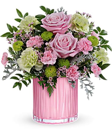 Pink roses, green carnations, and mixed blooms in a ribbed pink glass cylinder vase