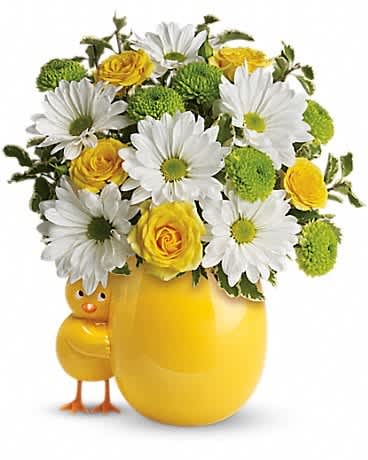 White daisies and yellow roses in a yellow egg-shaped vase with a small chick figure.