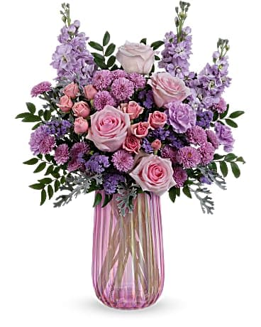 Tall arrangement of pink and lavender roses and mums in a ribbed pink glass vase