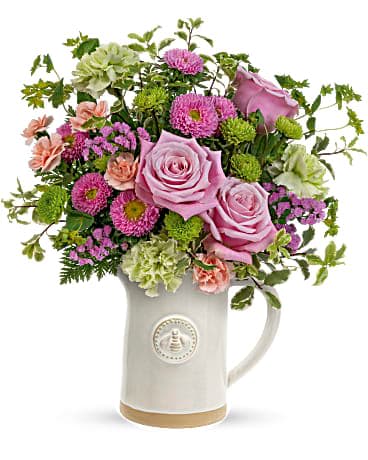 Pink and green mixed flower arrangement in a white ceramic pitcher