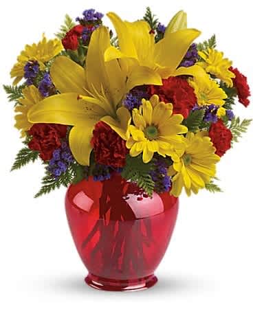 Bright bouquet of yellow lilies, yellow daisies and red carnations in a red glass vase