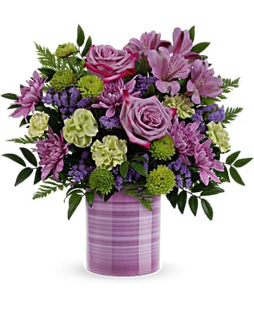 Lavender and green mixed flower arrangement with roses and mums in a striped lavender cylinder vase