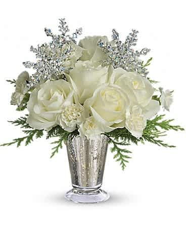 Compact arrangement of white roses and blooms with silver snowflakes in a silver vase