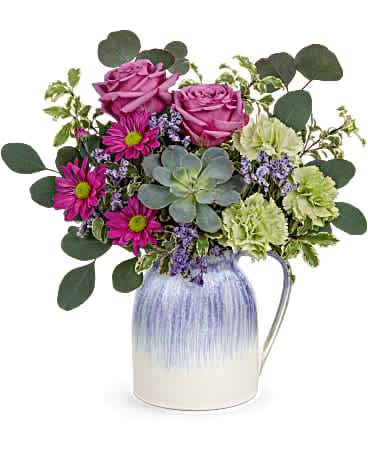 Mixed bouquet of pink roses, magenta daisies, green carnations and a succulent in a blue and white ceramic pitcher