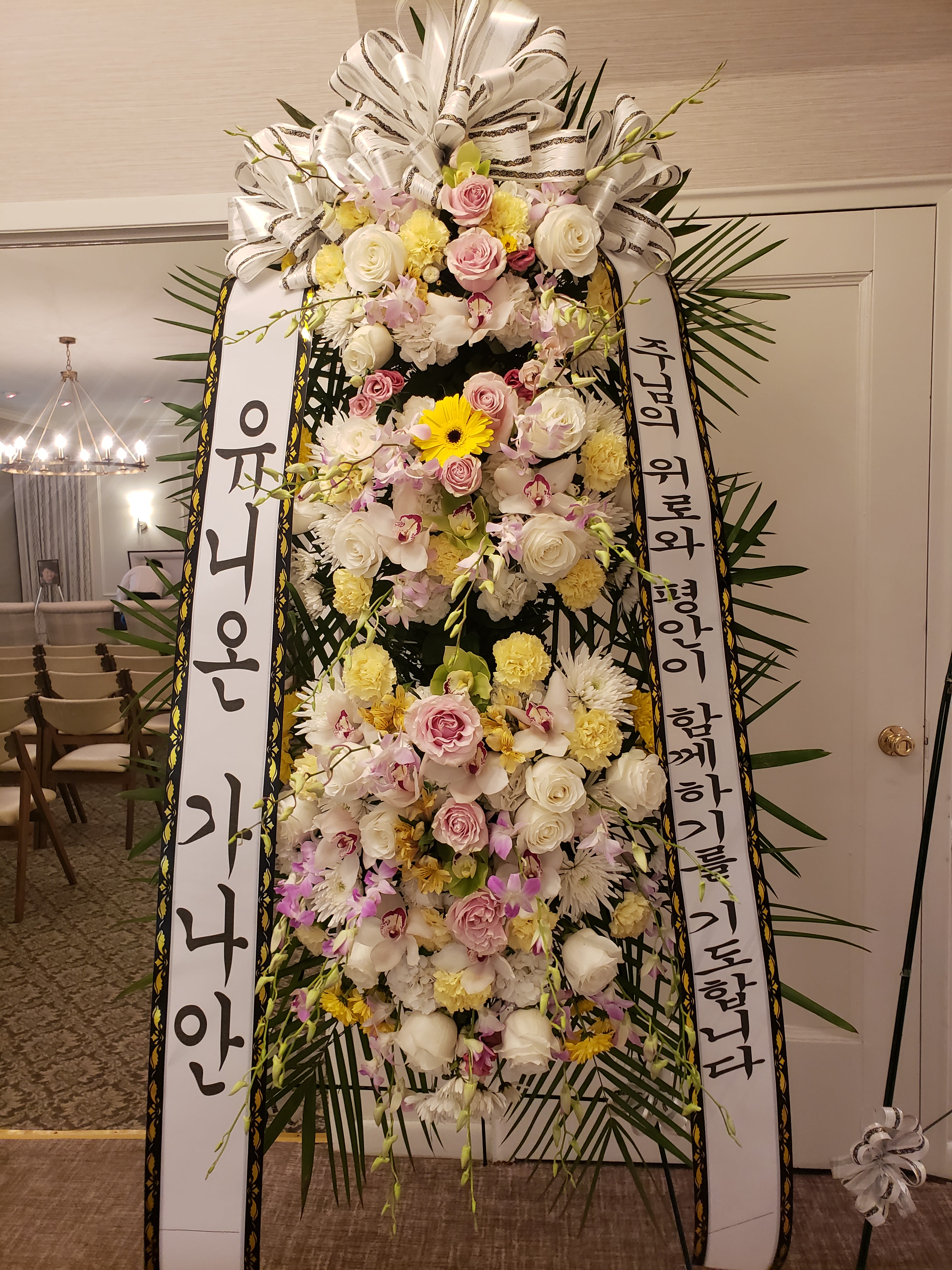 Tall standing floral wreath with white and pink flowers and Korean condolence ribbons