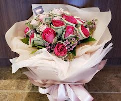 Bouquet of pink roses wrapped in white paper with a pink ribbon