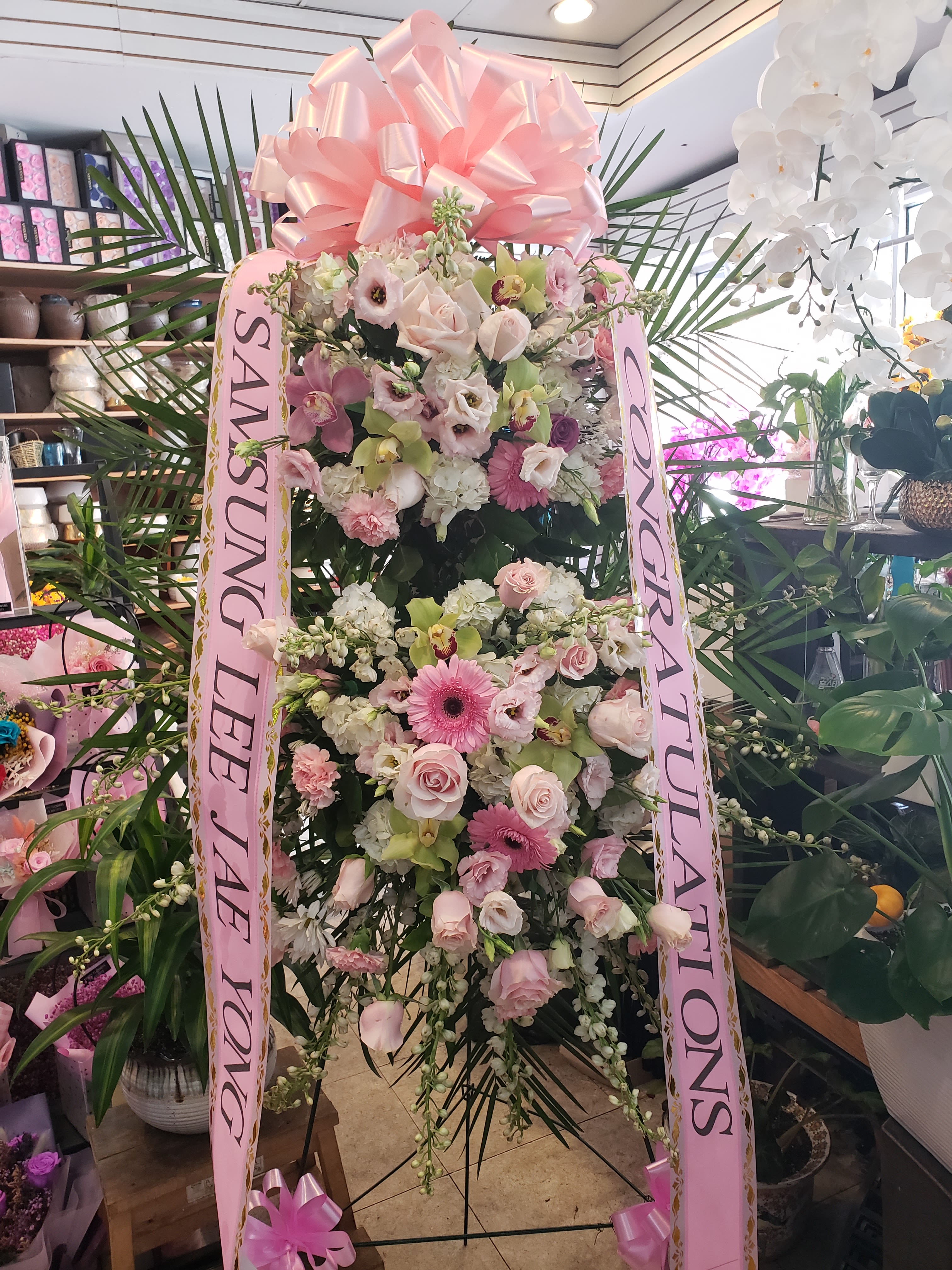 Tall pink and white floral standing spray with ribbon streamers