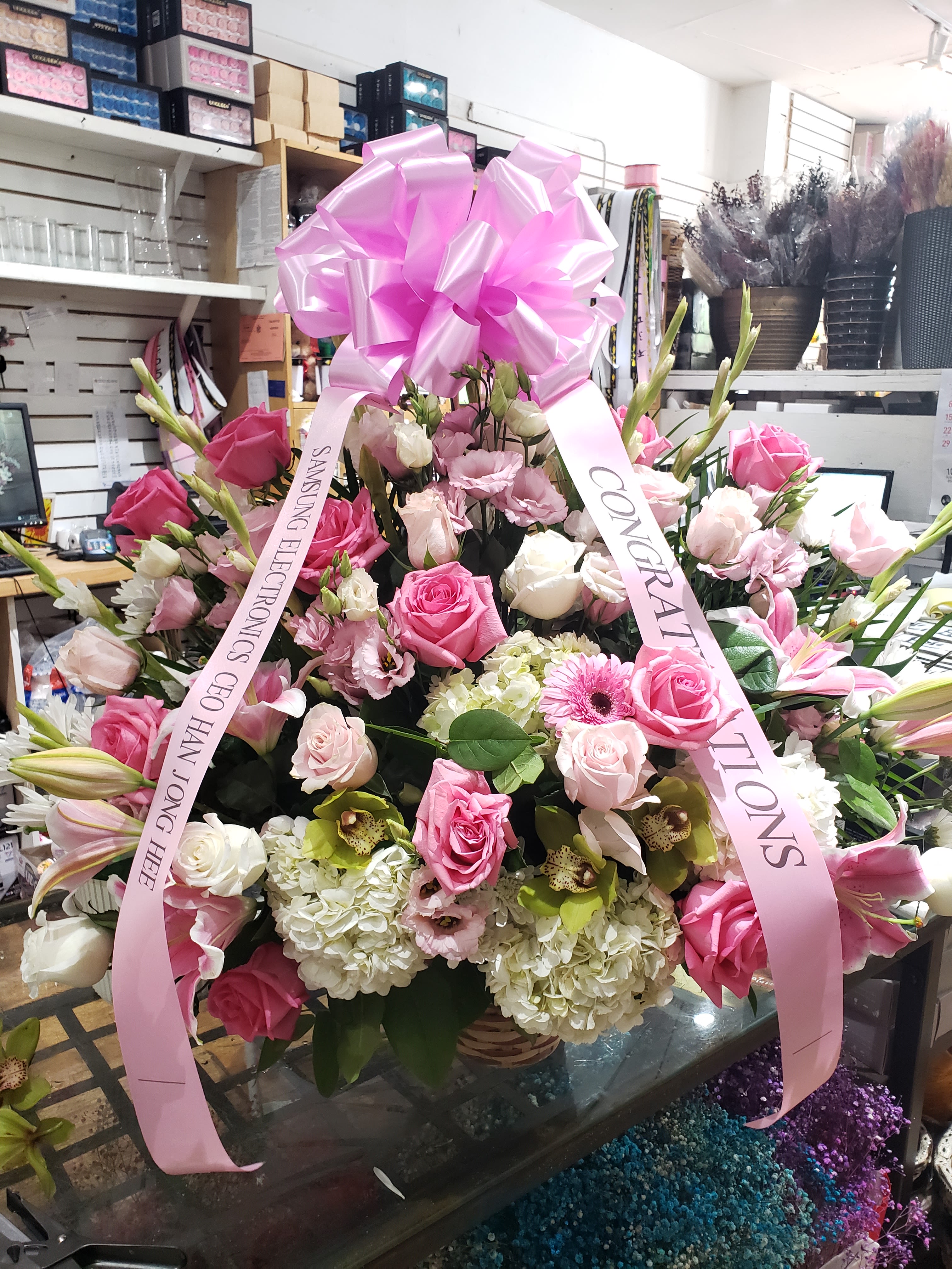 Large pink and white floral arrangement with a pink bow and ribbons