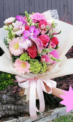 Pink and white mixed bouquet wrapped in white paper with a ribbon