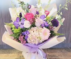 Bouquet of pink, purple, and white flowers wrapped in lavender paper