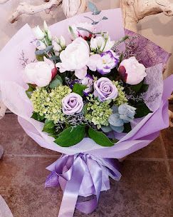 Lavender and white bouquet with roses and hydrangeas wrapped in purple paper