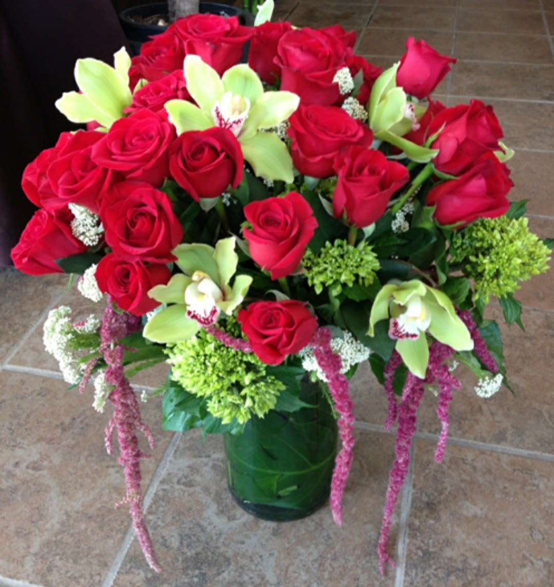 Bouquet of red roses and green orchids in a glass vase