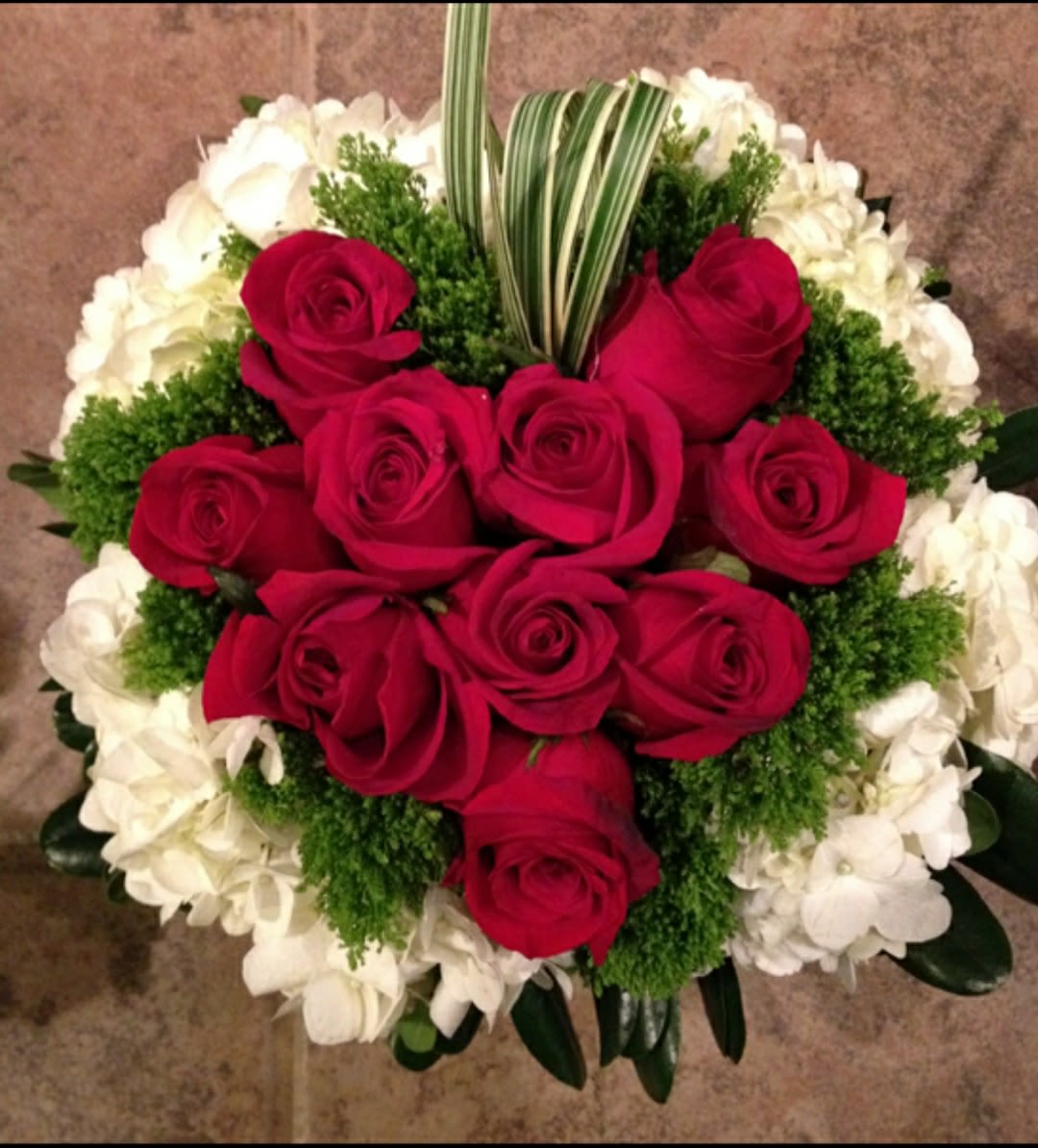 Red roses arranged with white flowers and greenery