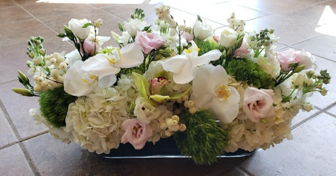 Low floral centerpiece with white orchids, hydrangeas, and pale pink blooms