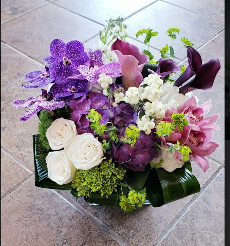 Purple orchids and white roses arranged in a low bouquet