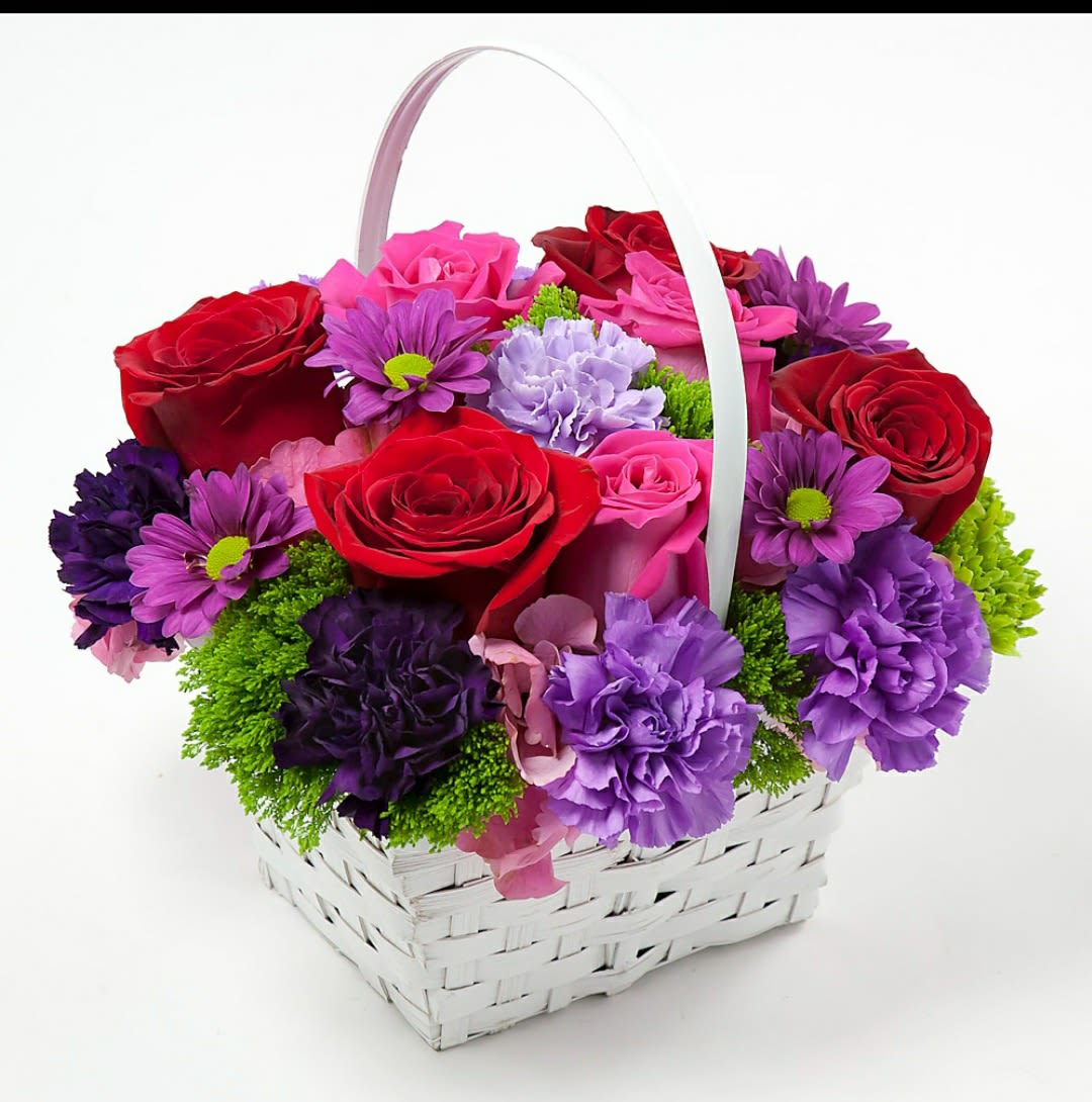 Basket of red, pink, and purple flowers with a white handle