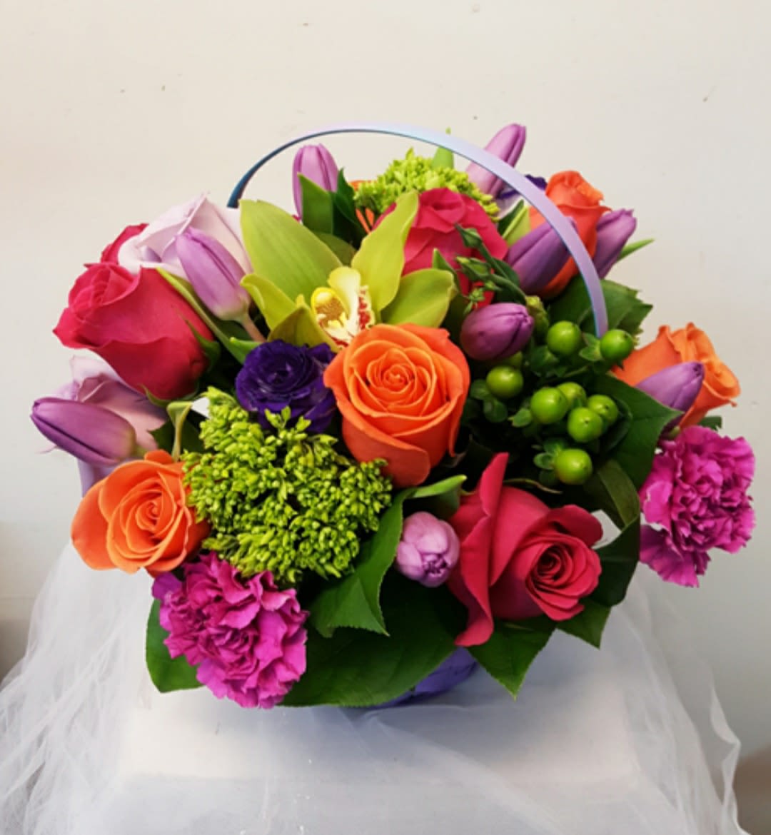 Colorful bouquet of roses, tulips, and orchids in a basket handle