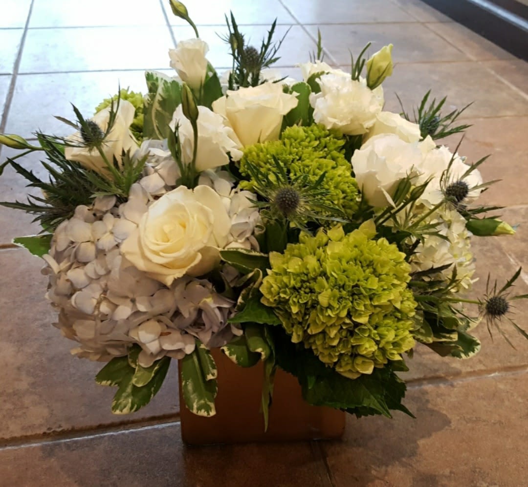 White roses and green hydrangeas in a low square container