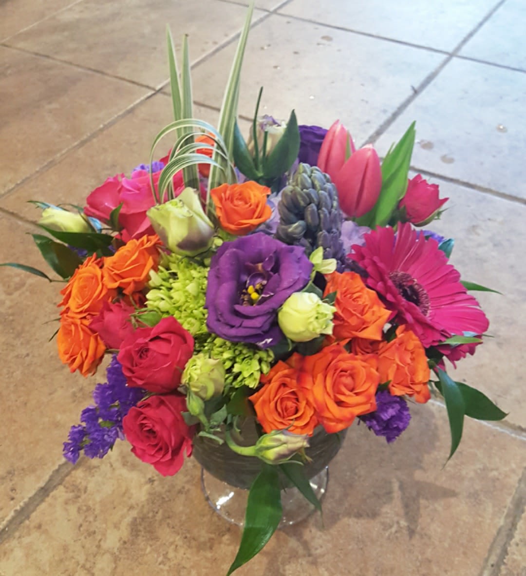 Colorful mixed bouquet in a clear glass vase with roses and gerbera daisies