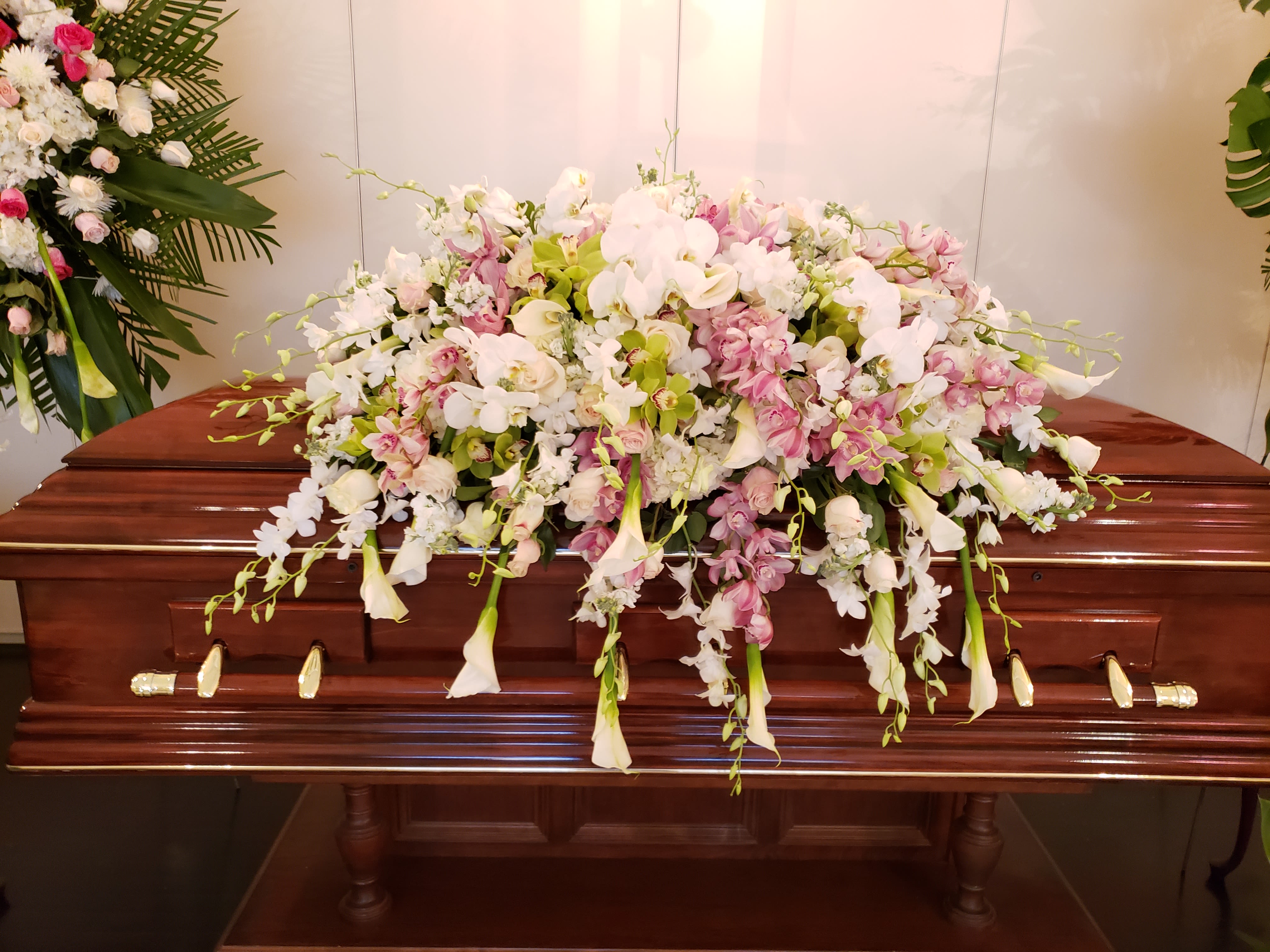 Large pastel floral spray on a casket with white and pink blooms