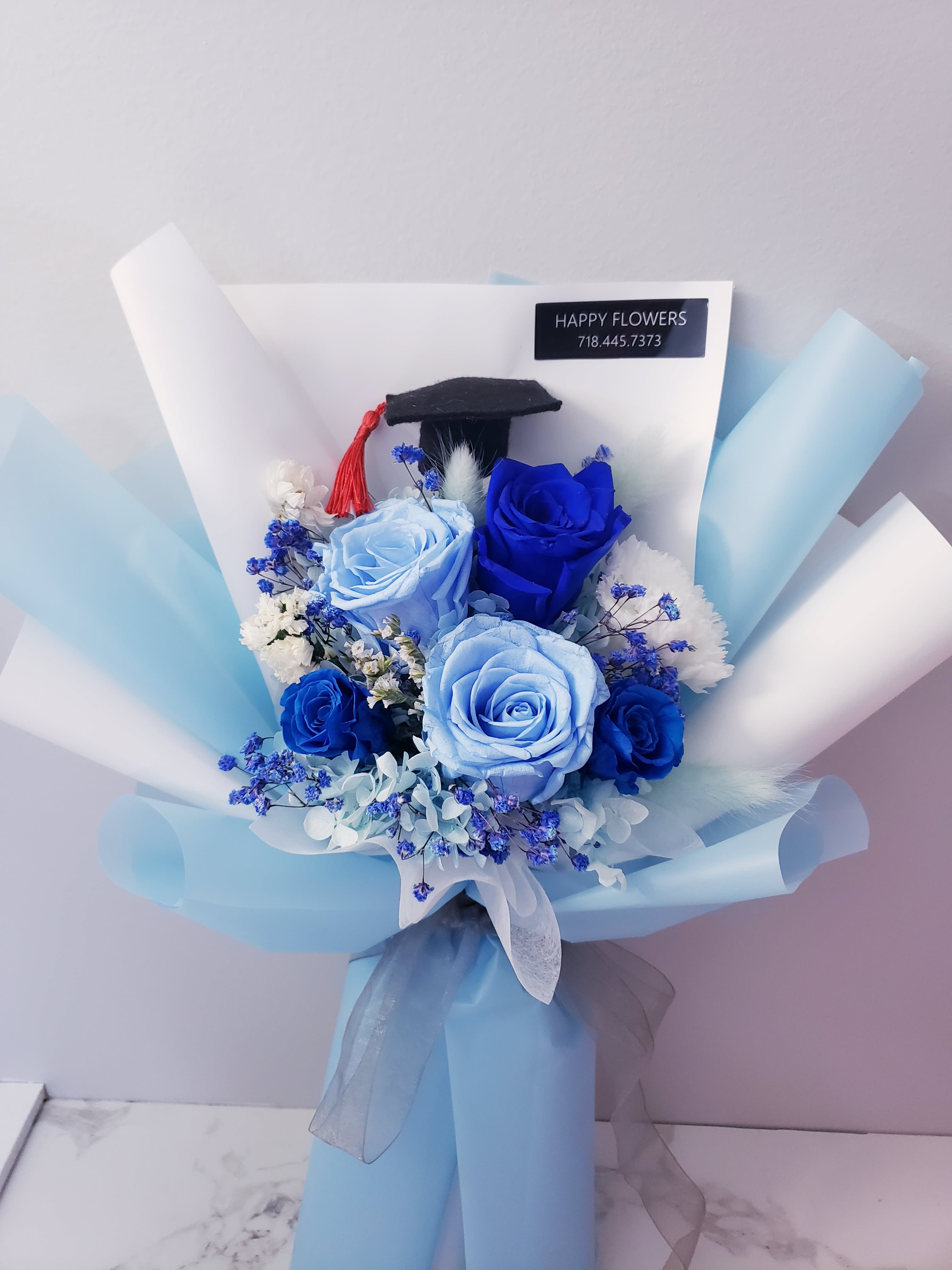 Blue rose bouquet with a graduation cap topper and light blue wrapping
