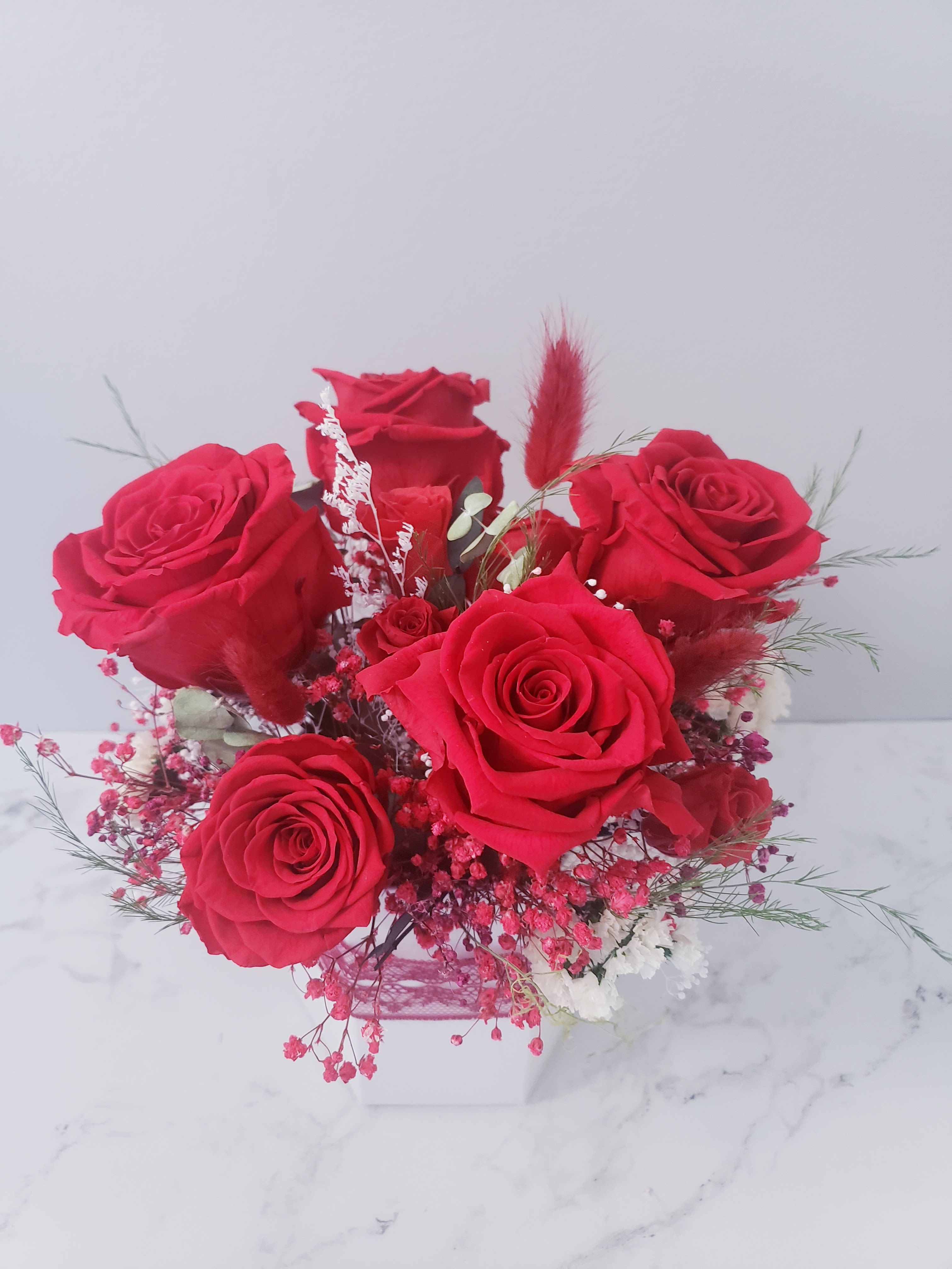 Bouquet of red roses in a white box with pink filler flowers