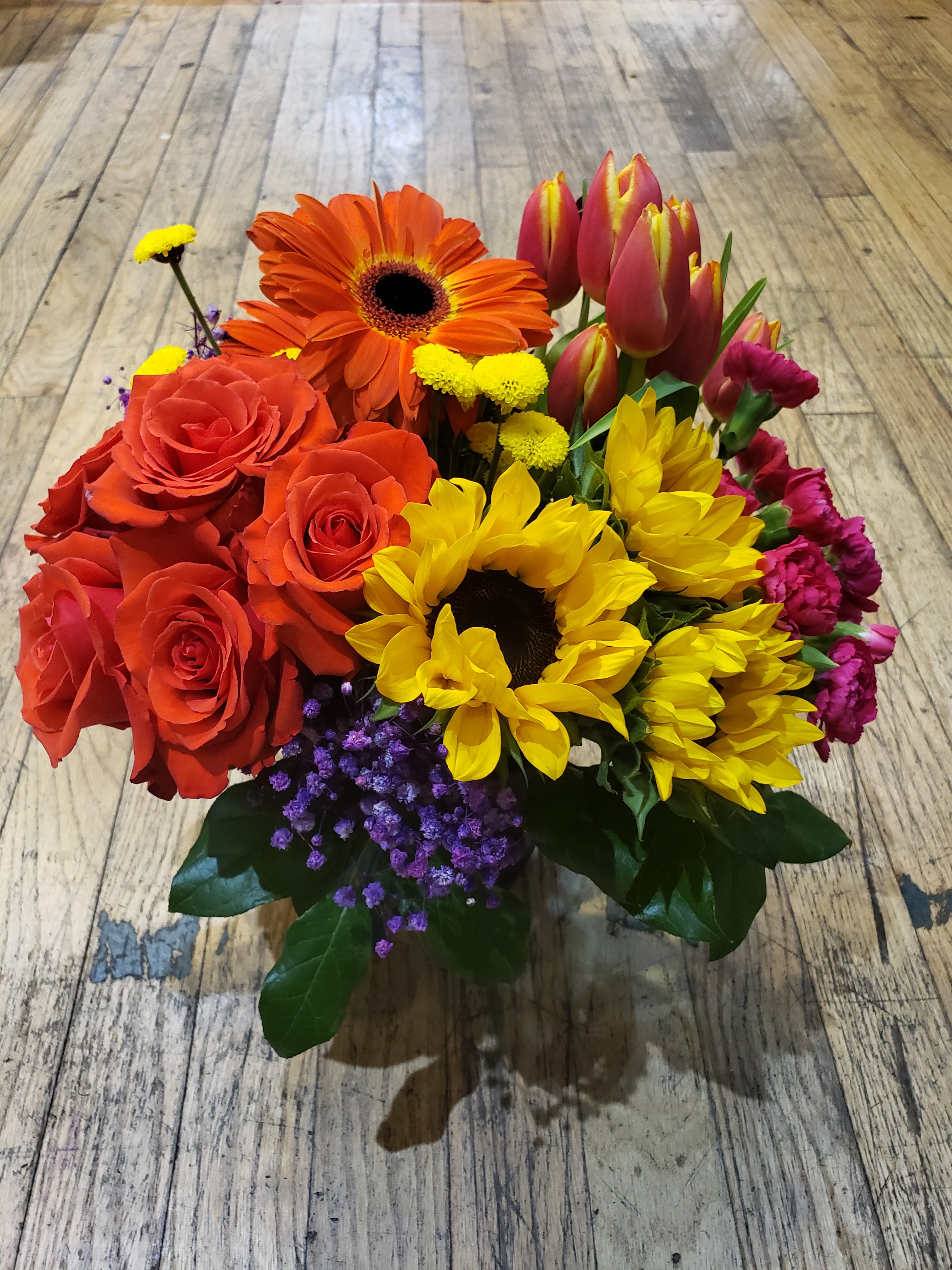 Bouquet of red roses, orange gerbera daisies, yellow sunflowers, and pink tulips