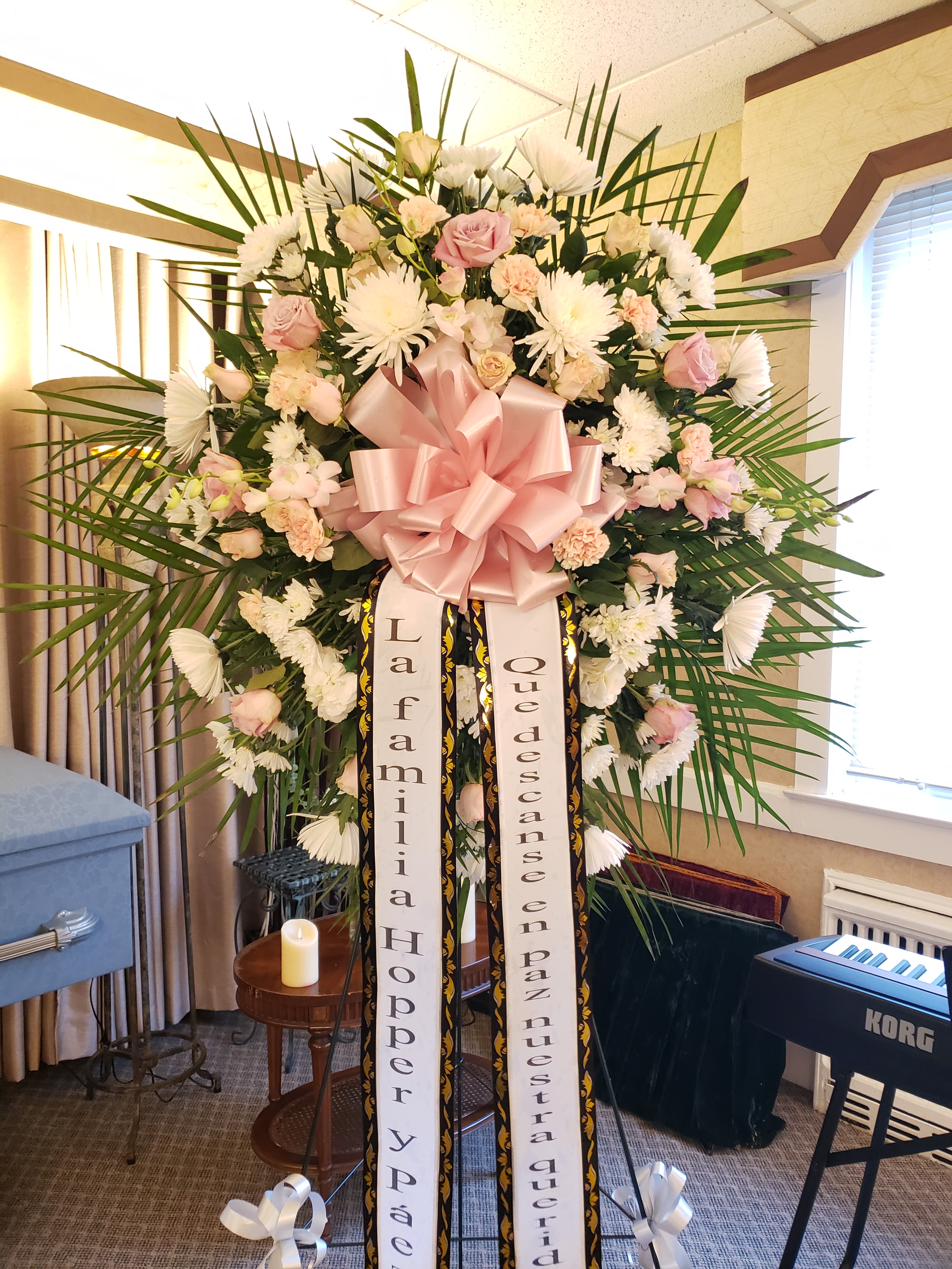 Large standing floral spray with pink and white flowers and a pink bow